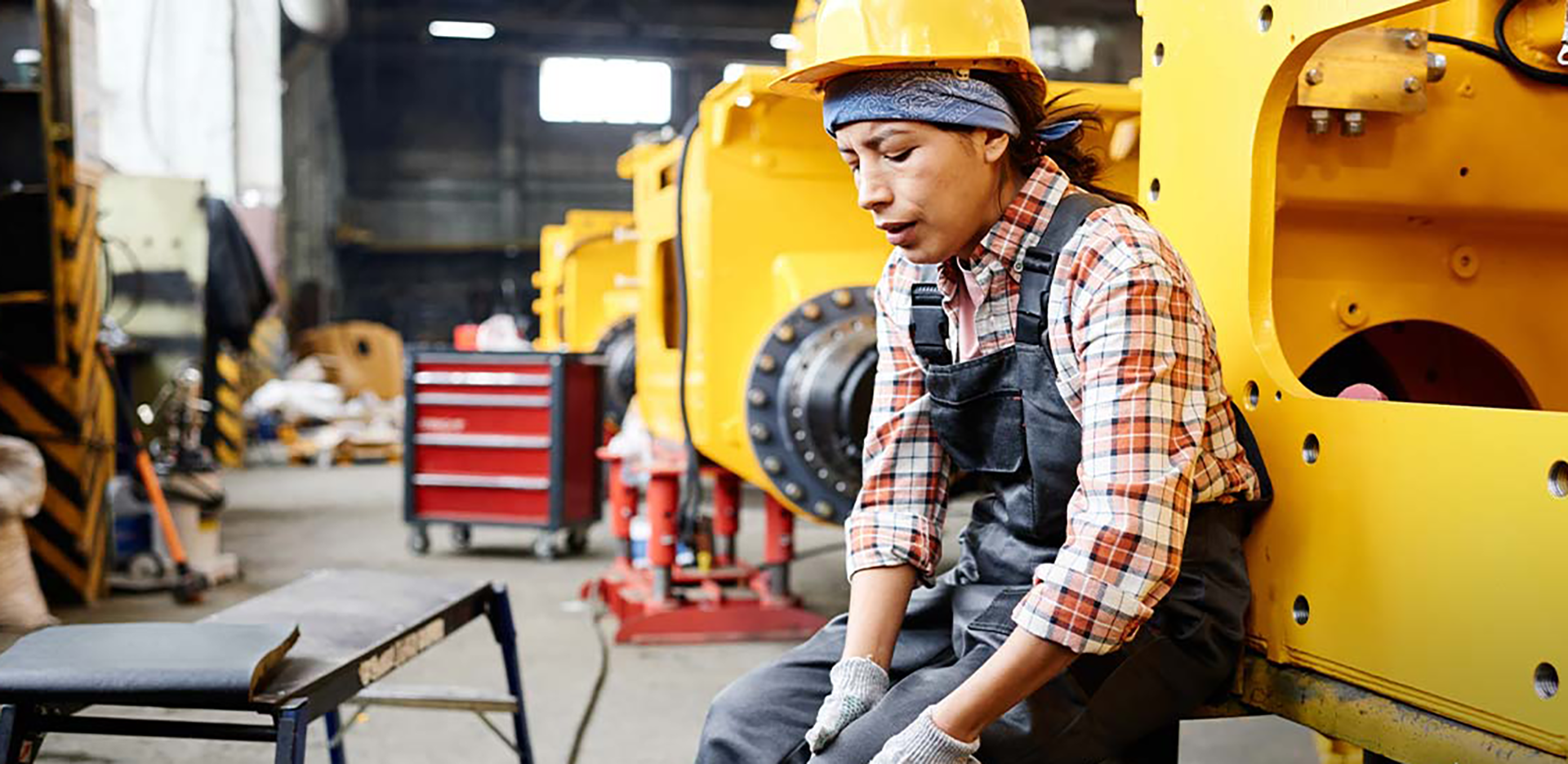 A construction worker sitting and clutching her knee.