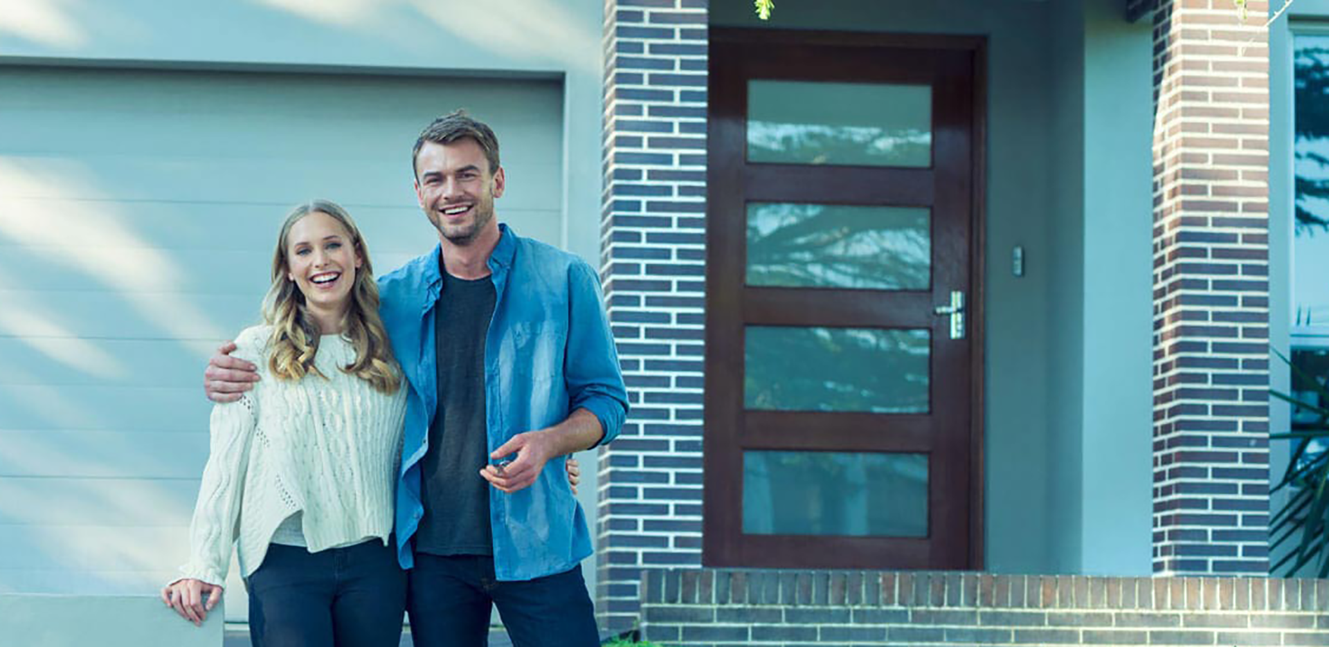 A smiling couple holding the keys to their new home.