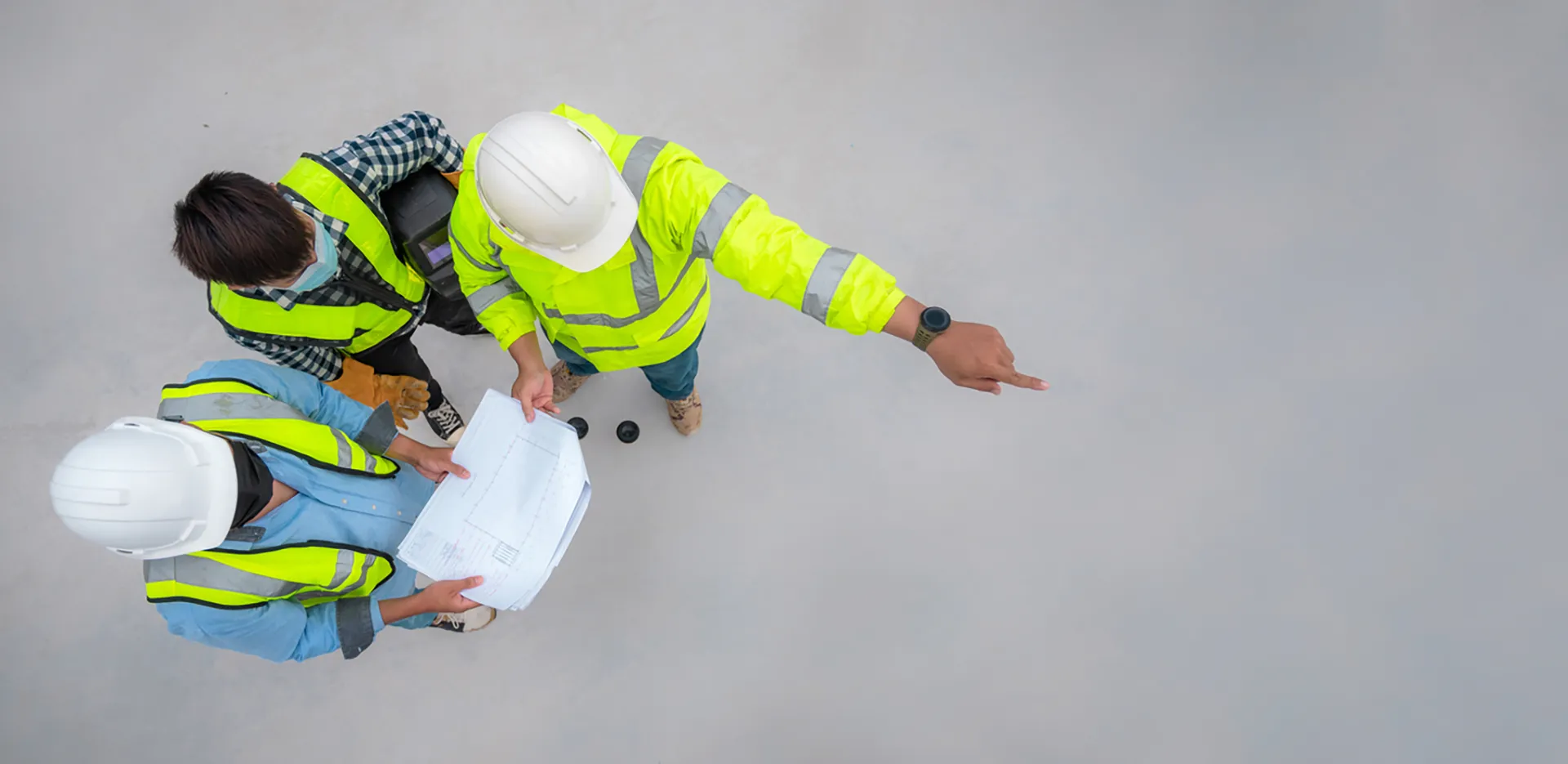 A bird's eye view of a trio of construction workers reviewing blueprints.