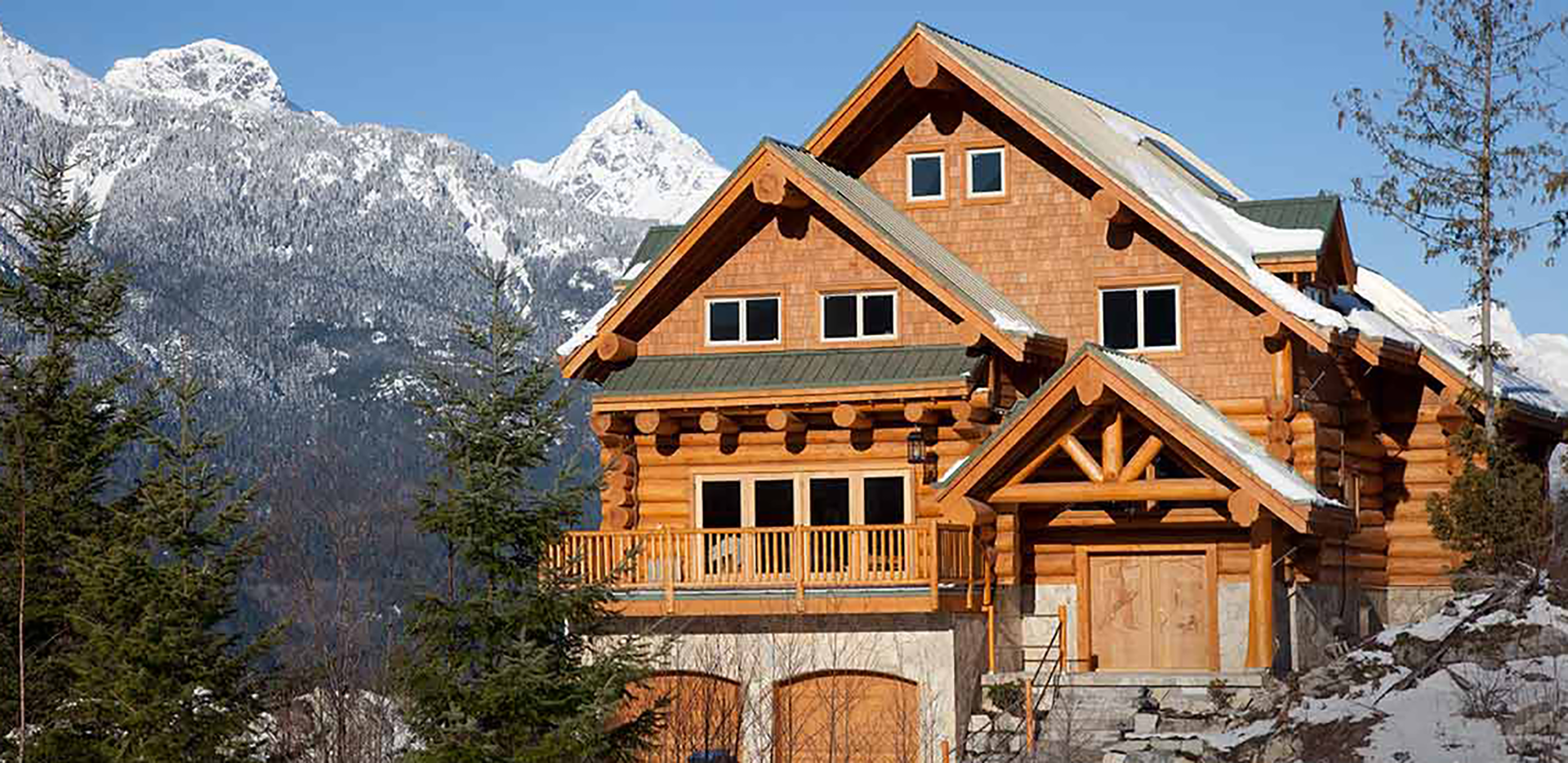 A log house in front of a mountain range.