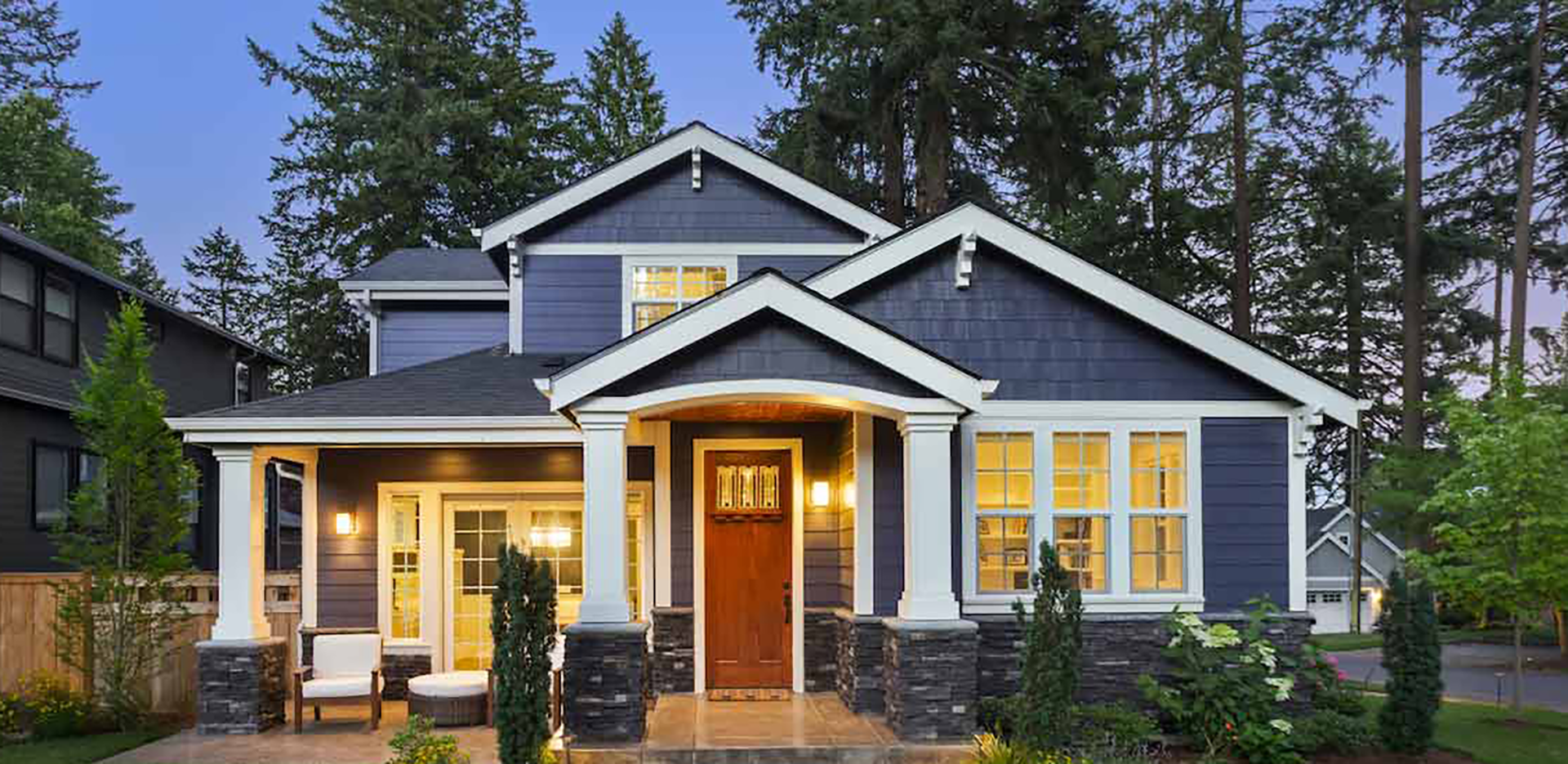 An exterior shot of a grey home with the lights on.