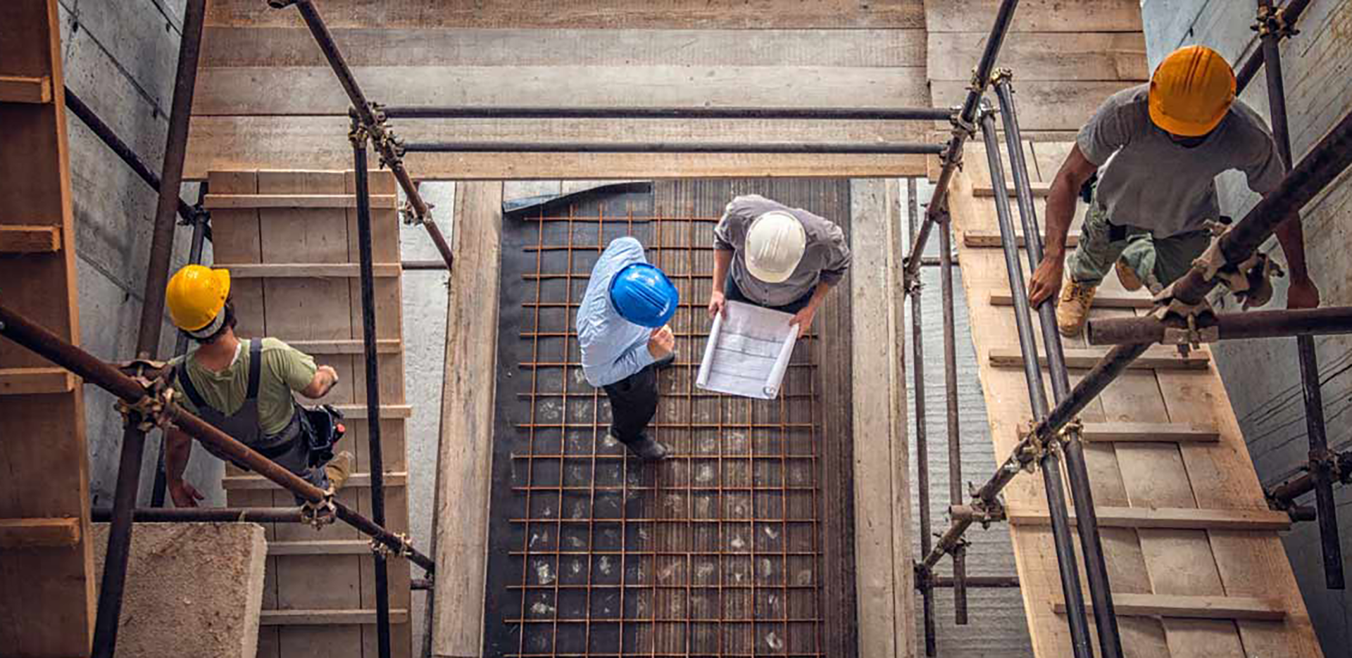 A bird's eye view of four contractors wearing hard hats on a job site.