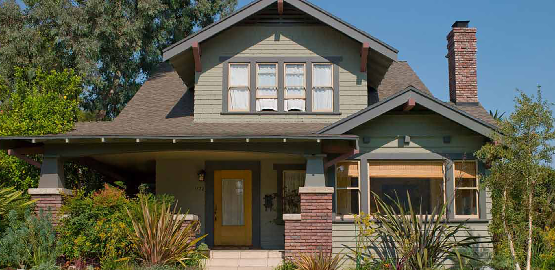 An exterior shot of a green-painted home in the daytime.