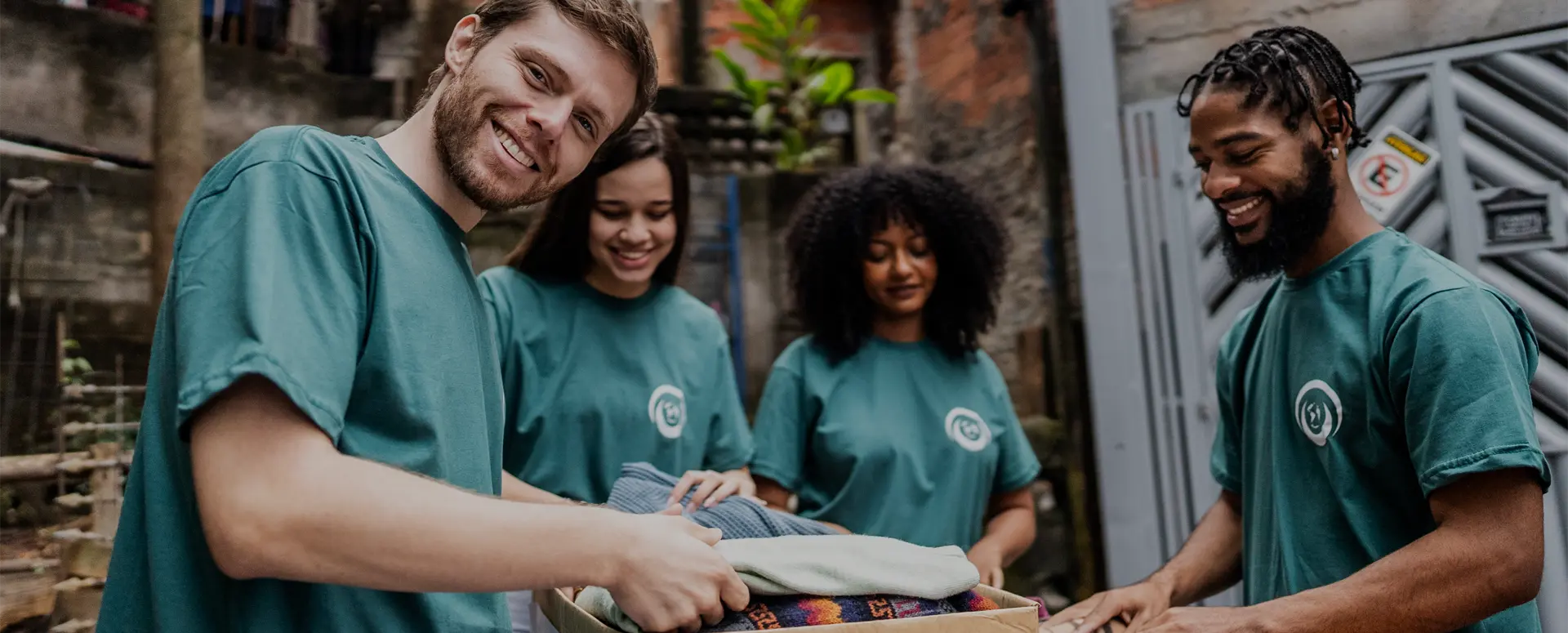A group of people in identical t-shirts folding and placing clothes into boxes.
