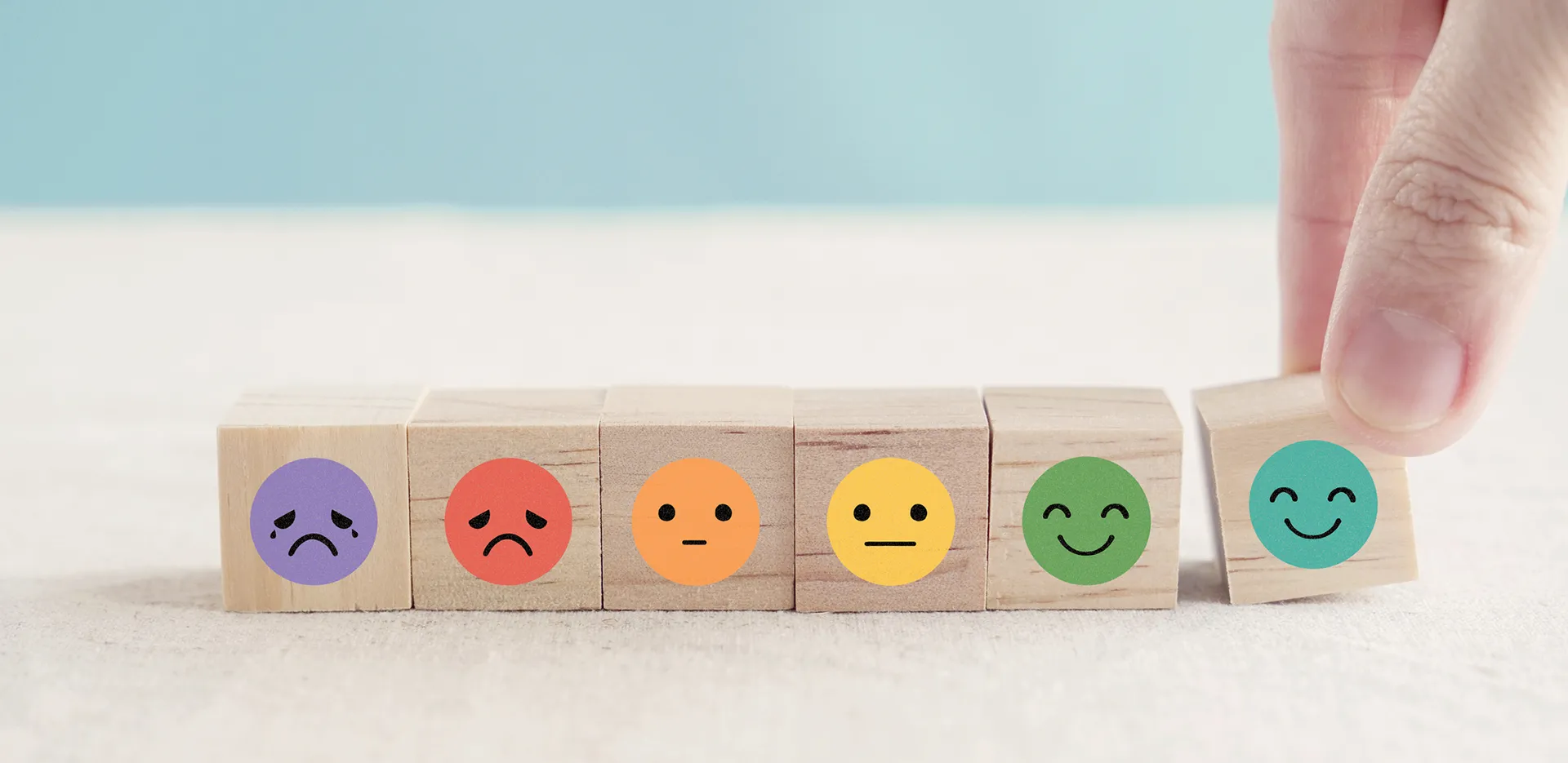 A series of wooden blocks with images of faces portraying different emotions on them.