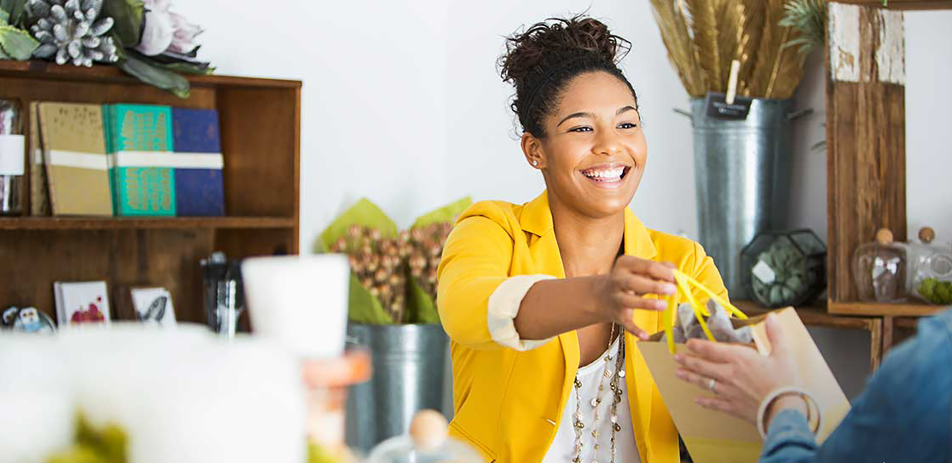 A smiling entrepreneur handing a bag to a customer.