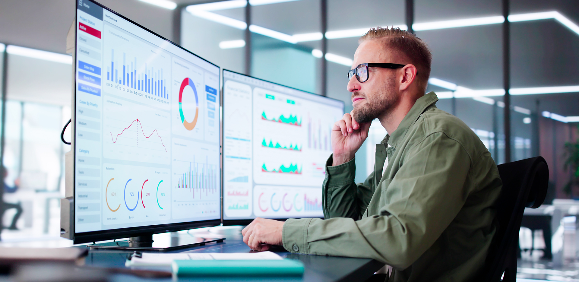 A professional sitting in front of a pair of computer monitors showing assorted graphs.