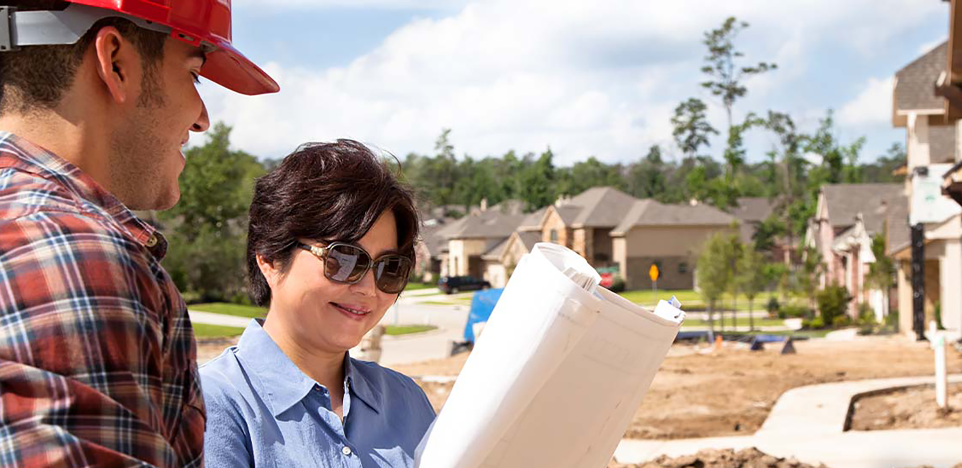 A homeowner and a contractor looking at a set of blueprints.