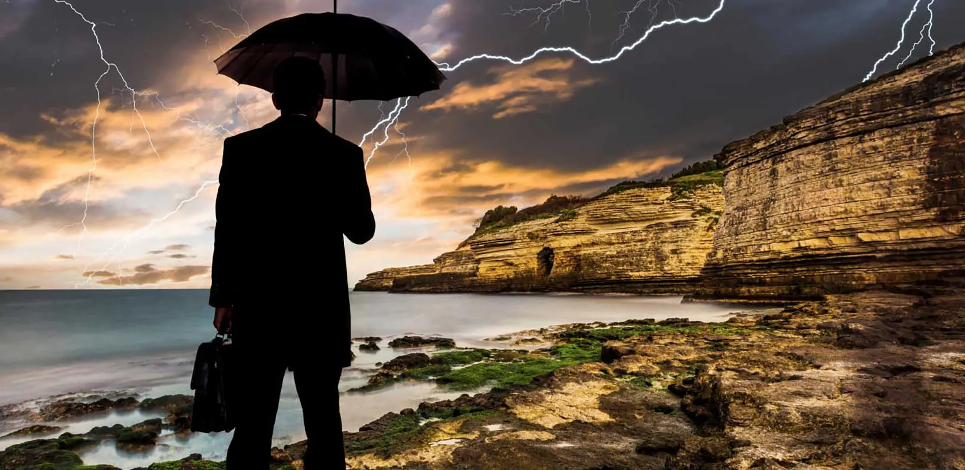 The silhouette of a person holding an umbrella with a lightning strike in the background.