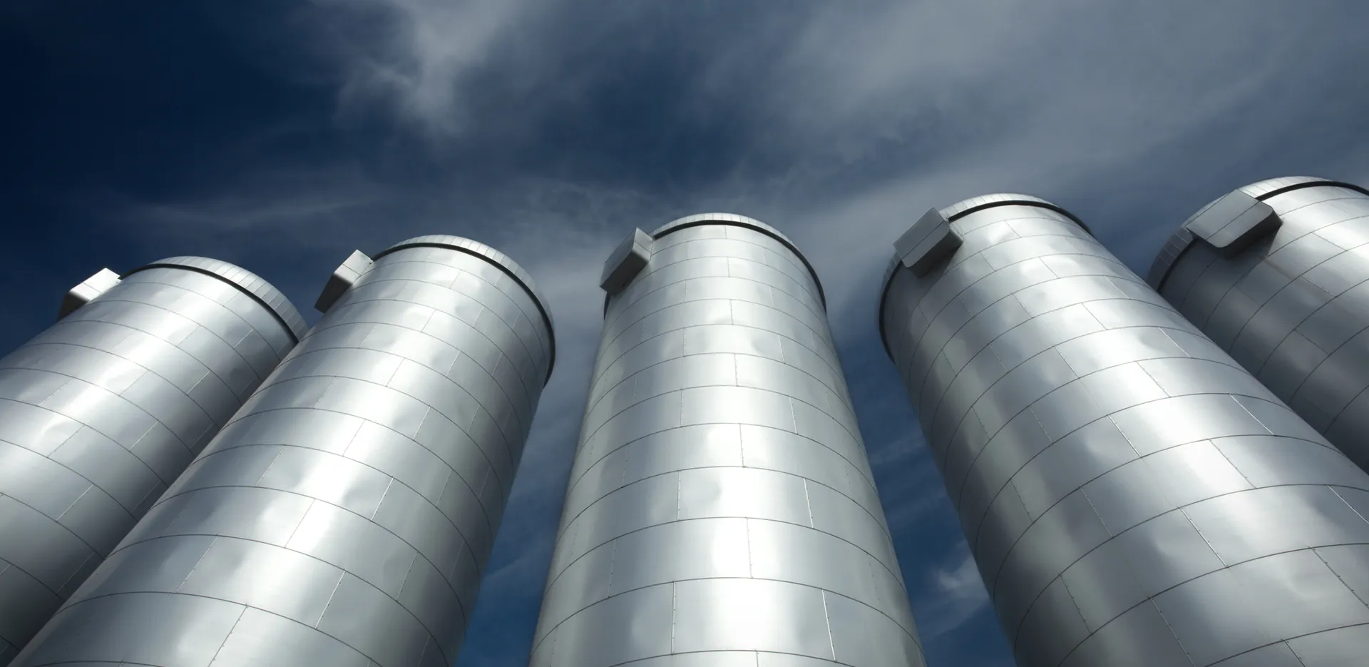 An image looking up at 5 silver silos.