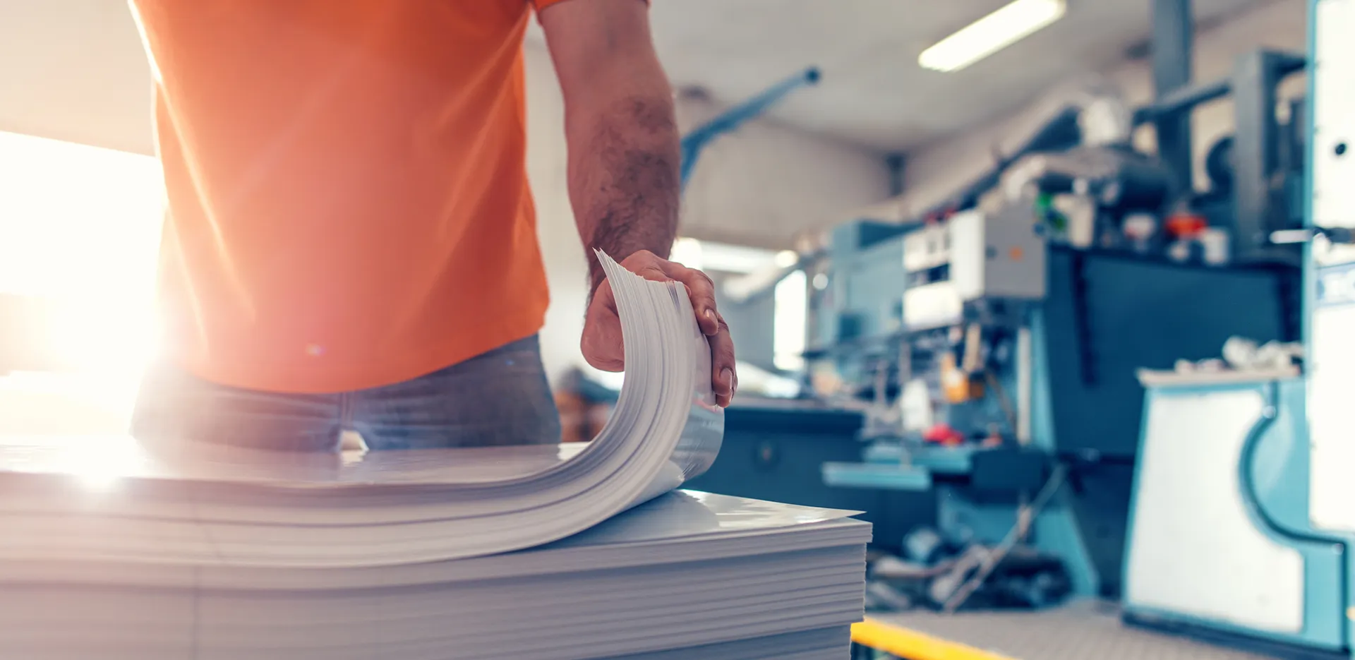A person in an orange t-shirt flipping through a stack of paper.