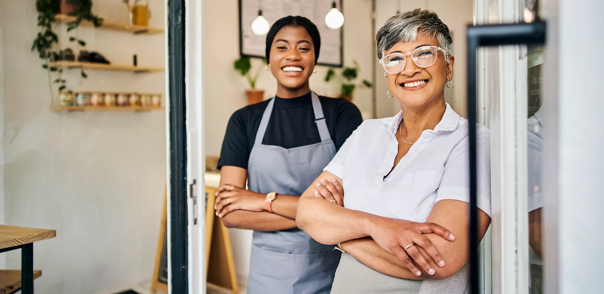 A pair of smiling women standing in the doorway of their business.
