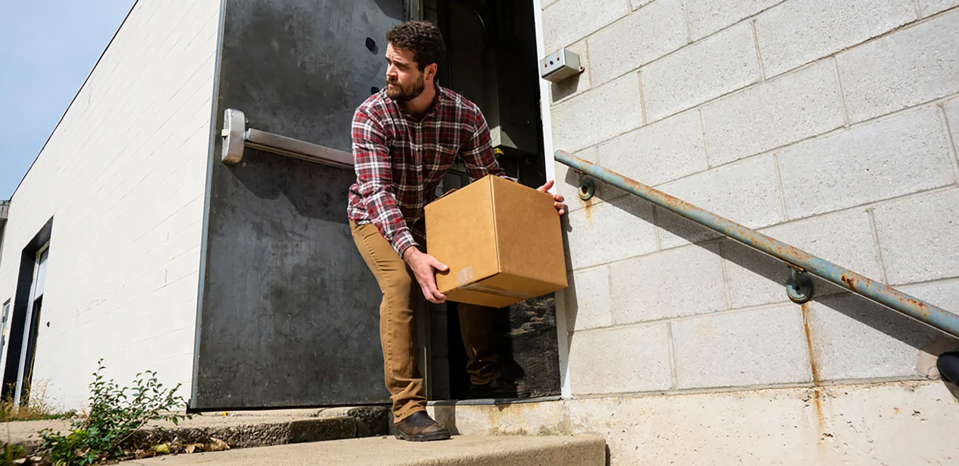A man picking a package up off of a set of concrete steps.