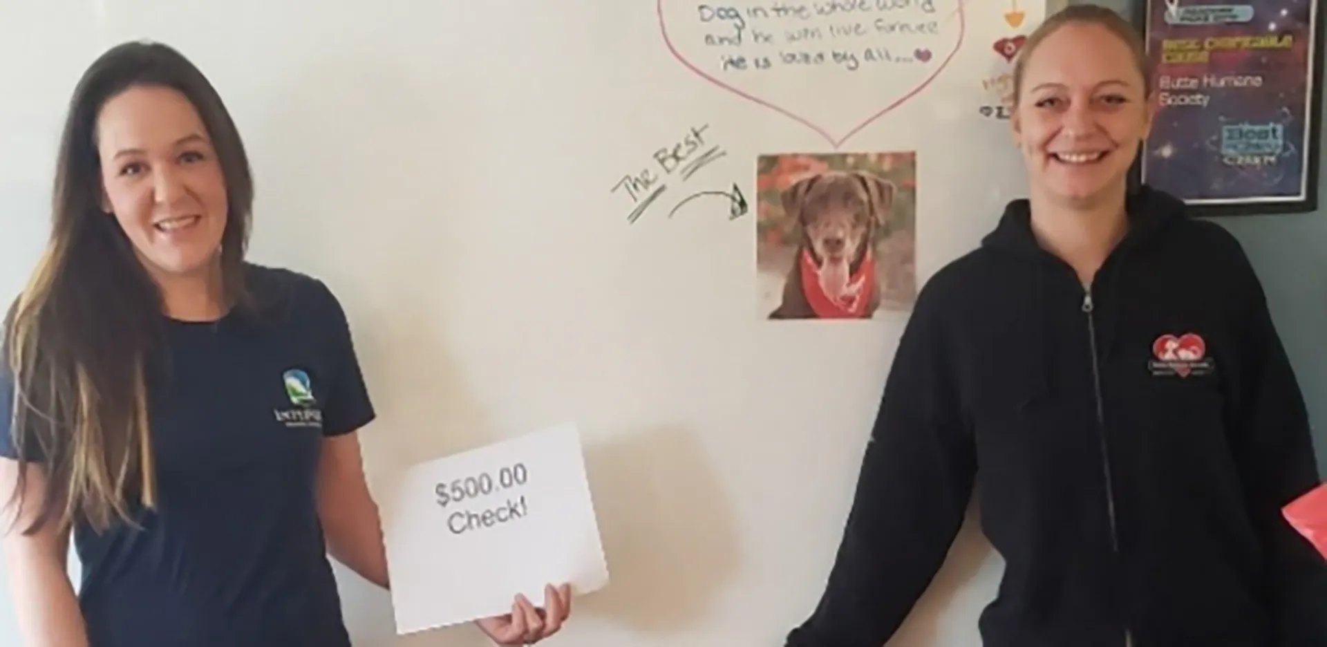 An InterWest team member handing a piece of paper reading '$500 Check' to a member of the Butte Humane Society.