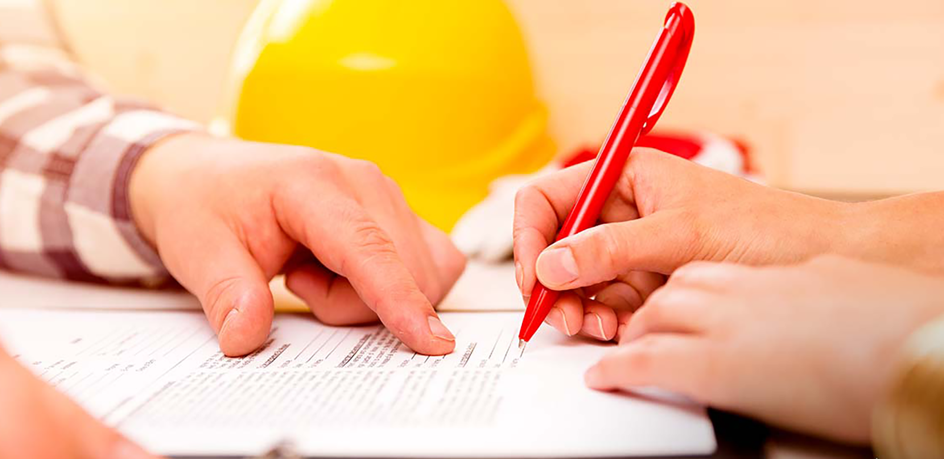 A view of someone's hands filling out a form with red pen.