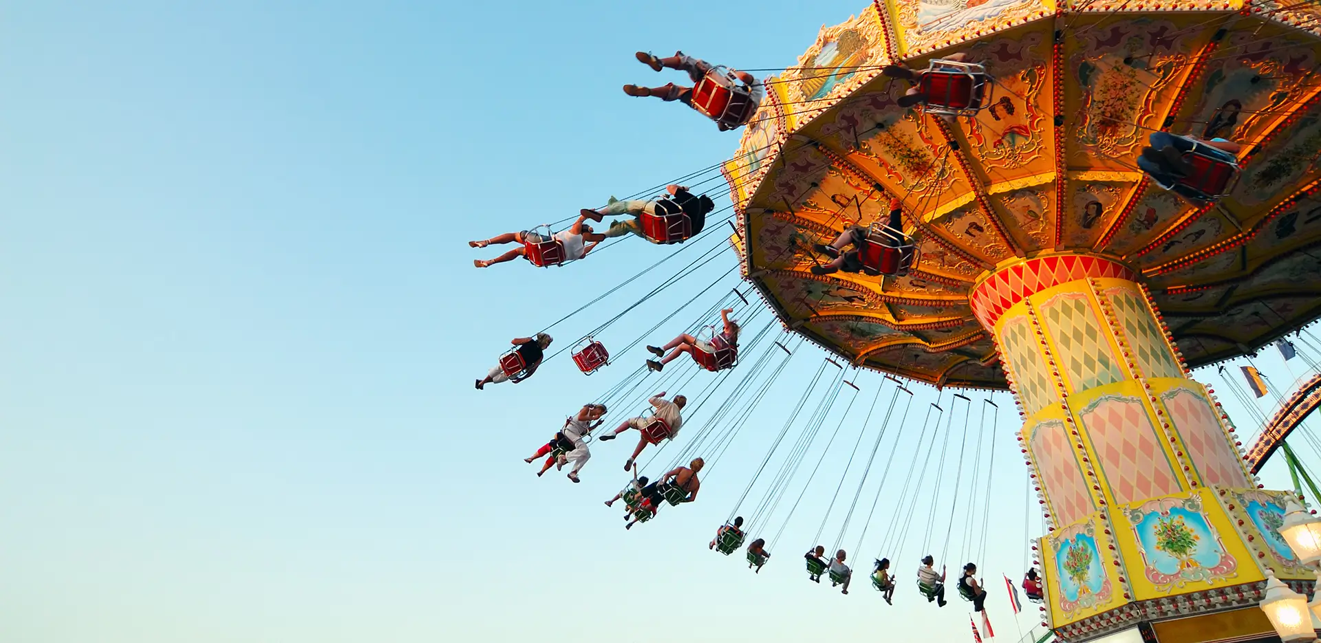 A view looking up at a swing ride at an amusement park.