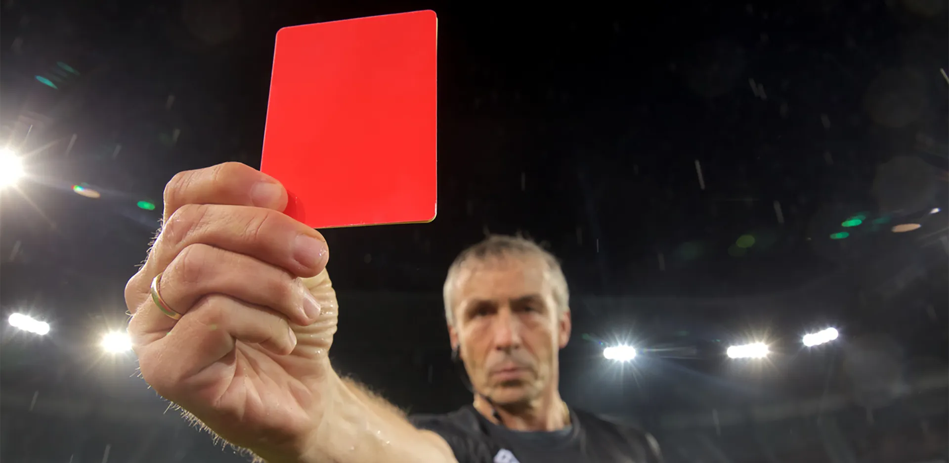 A referee at a soccer match holding a red card.