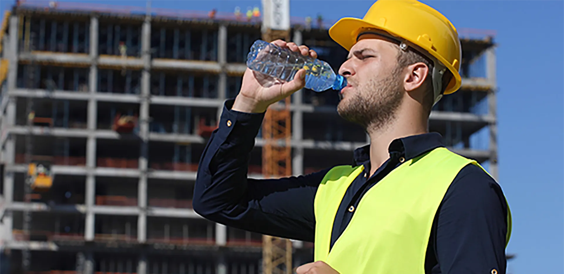 A construction worker drinking from a water bottle.