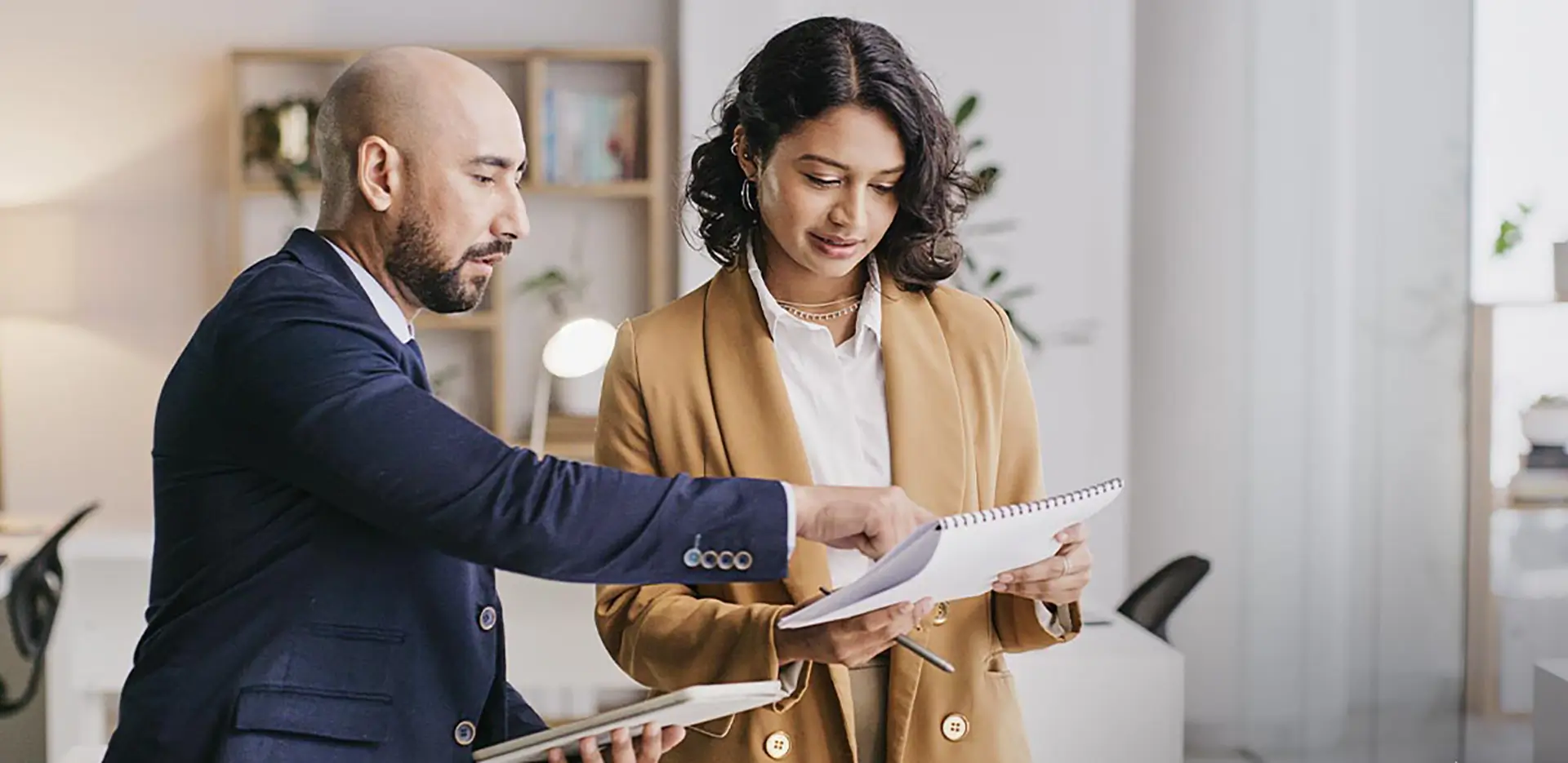 A pair of professionals reviewing information in a notebook.