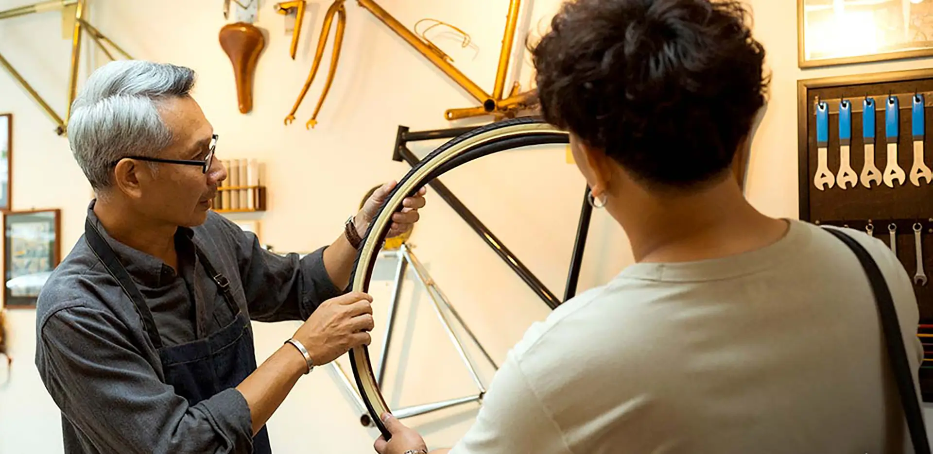 A bike shop employee and a customer looking at a bicycle tire.