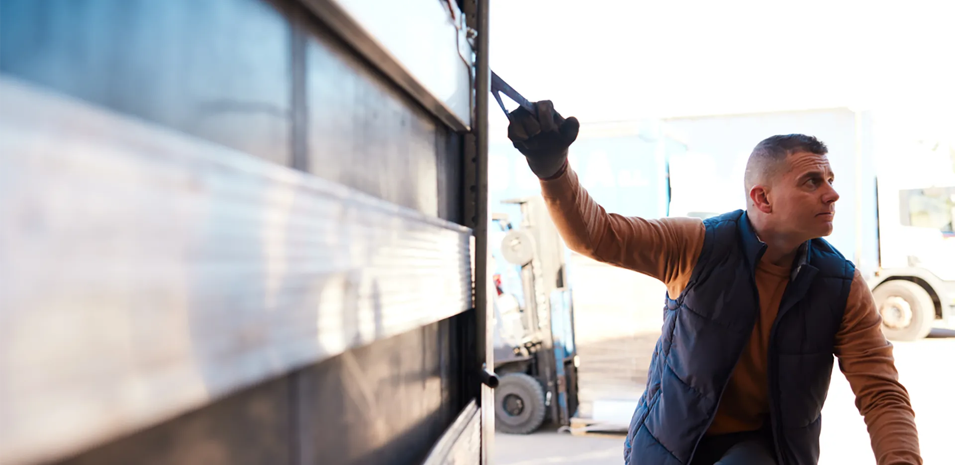 A transportation worker closing the back of a truck.