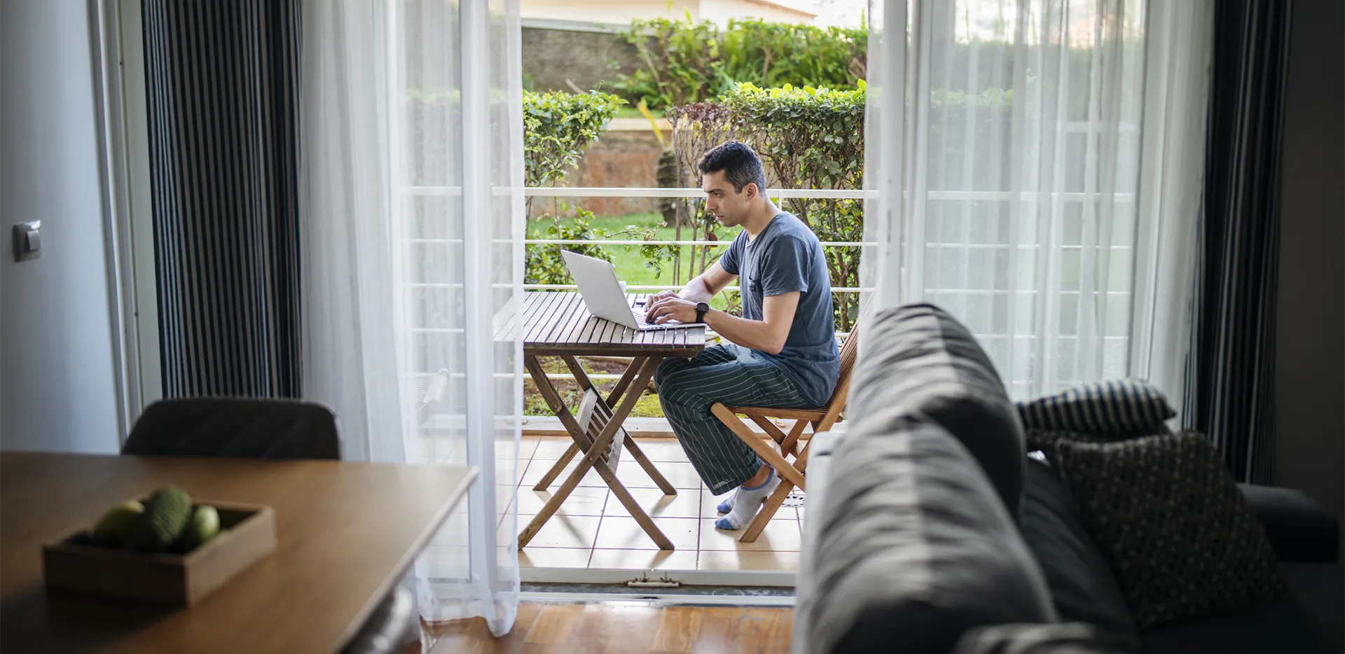 A person typing on their laptop while working on their patio.