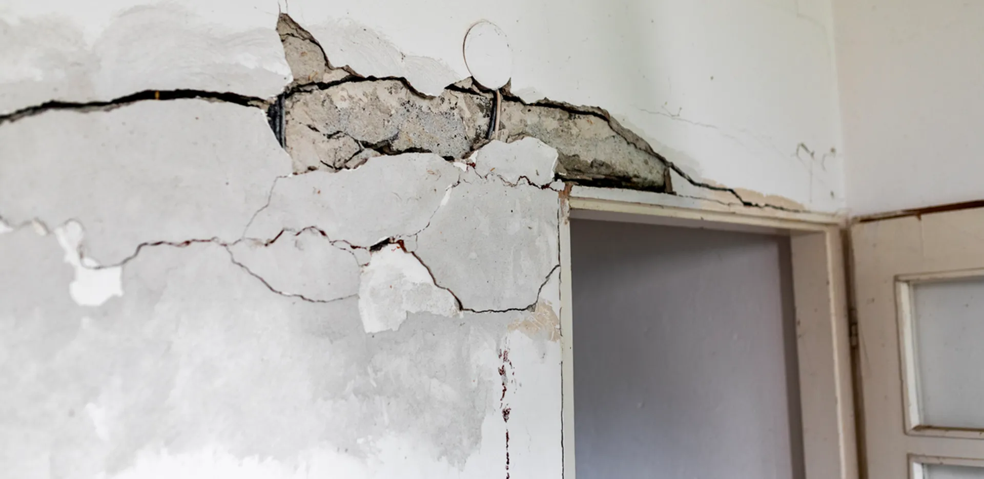 A doorway with a badly cracked wall above it.