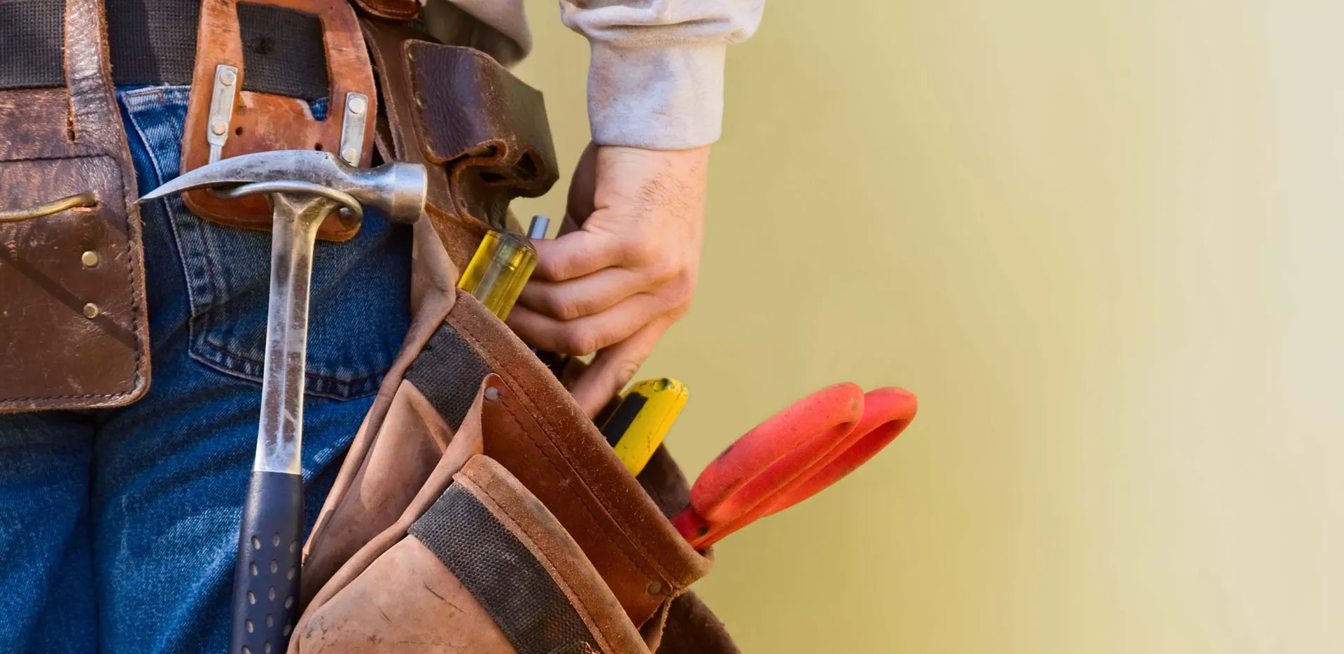 A close-up of a contractor grabbing a tool from a pouch at their hip.