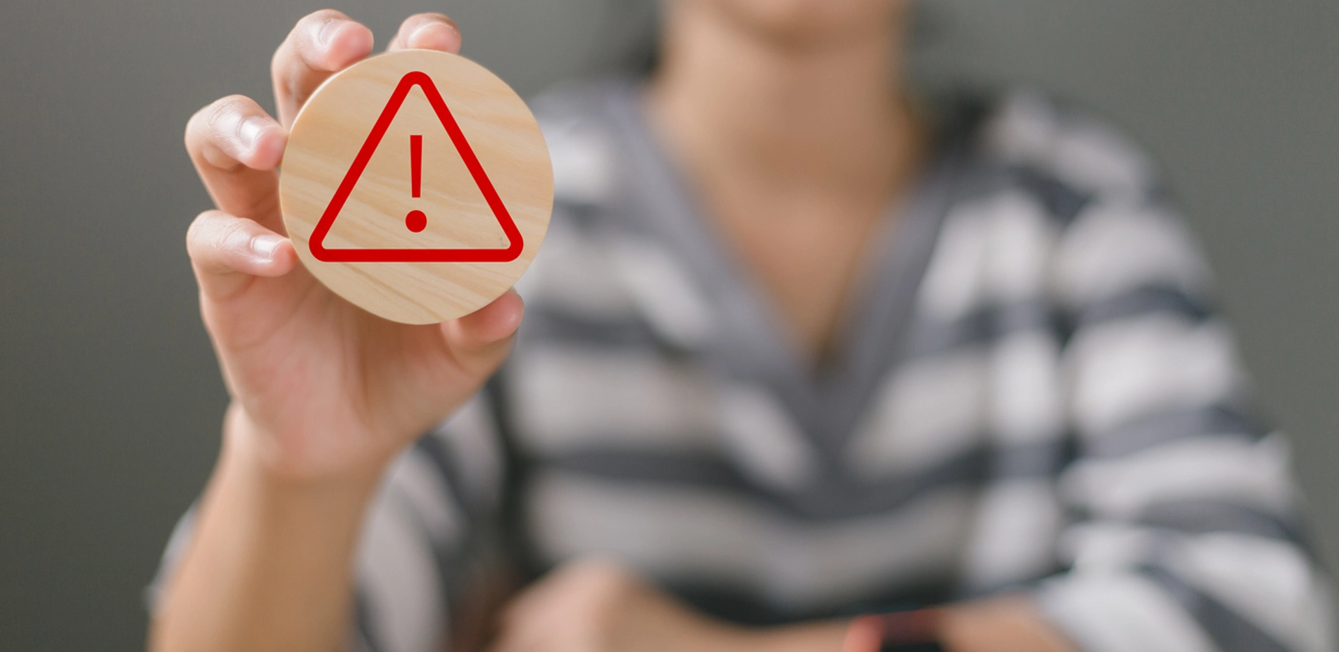 woman's hands holding a circular wood with warning or caution sign