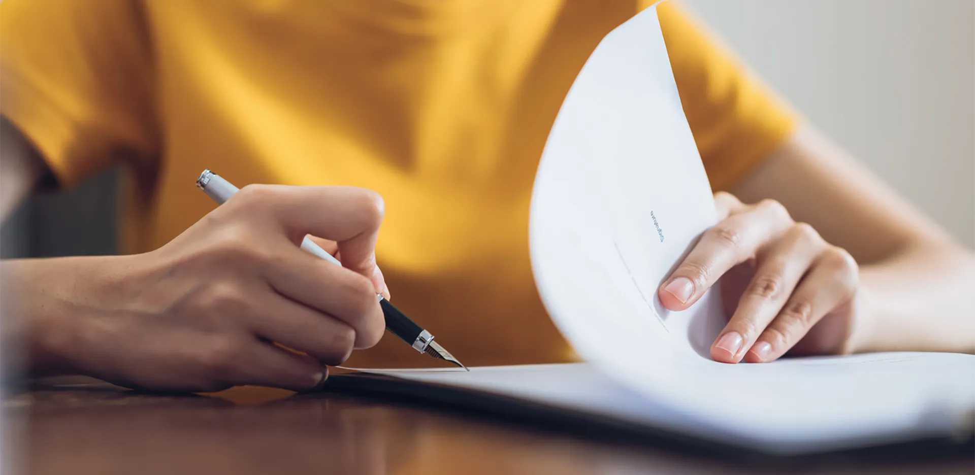 A close up of someone's hands as they're filling out paperwork.