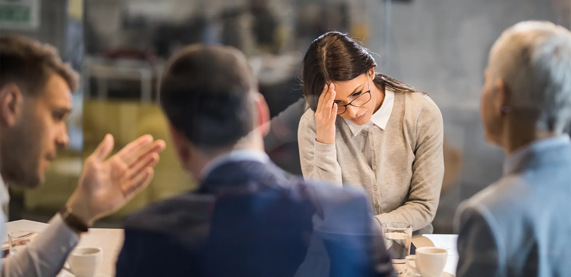 A professional woman in a meeting looking stressed.