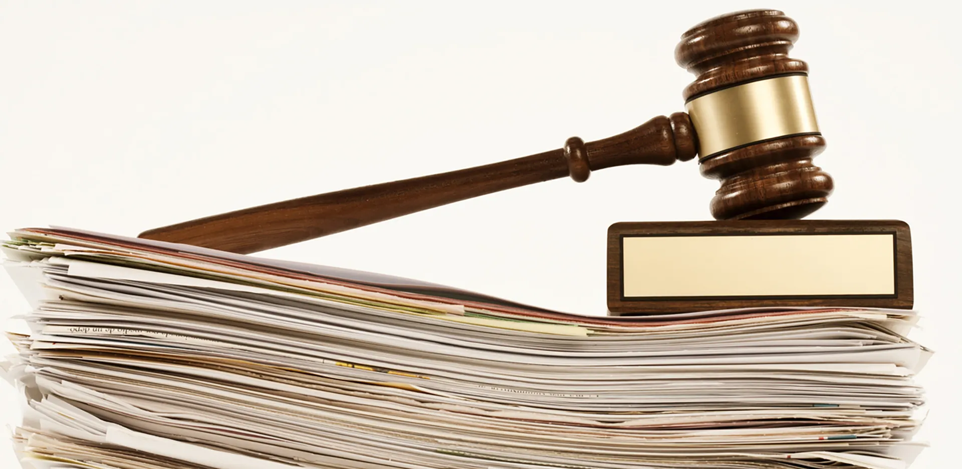 A gavel and sounding block rest on top of a stack of folders.