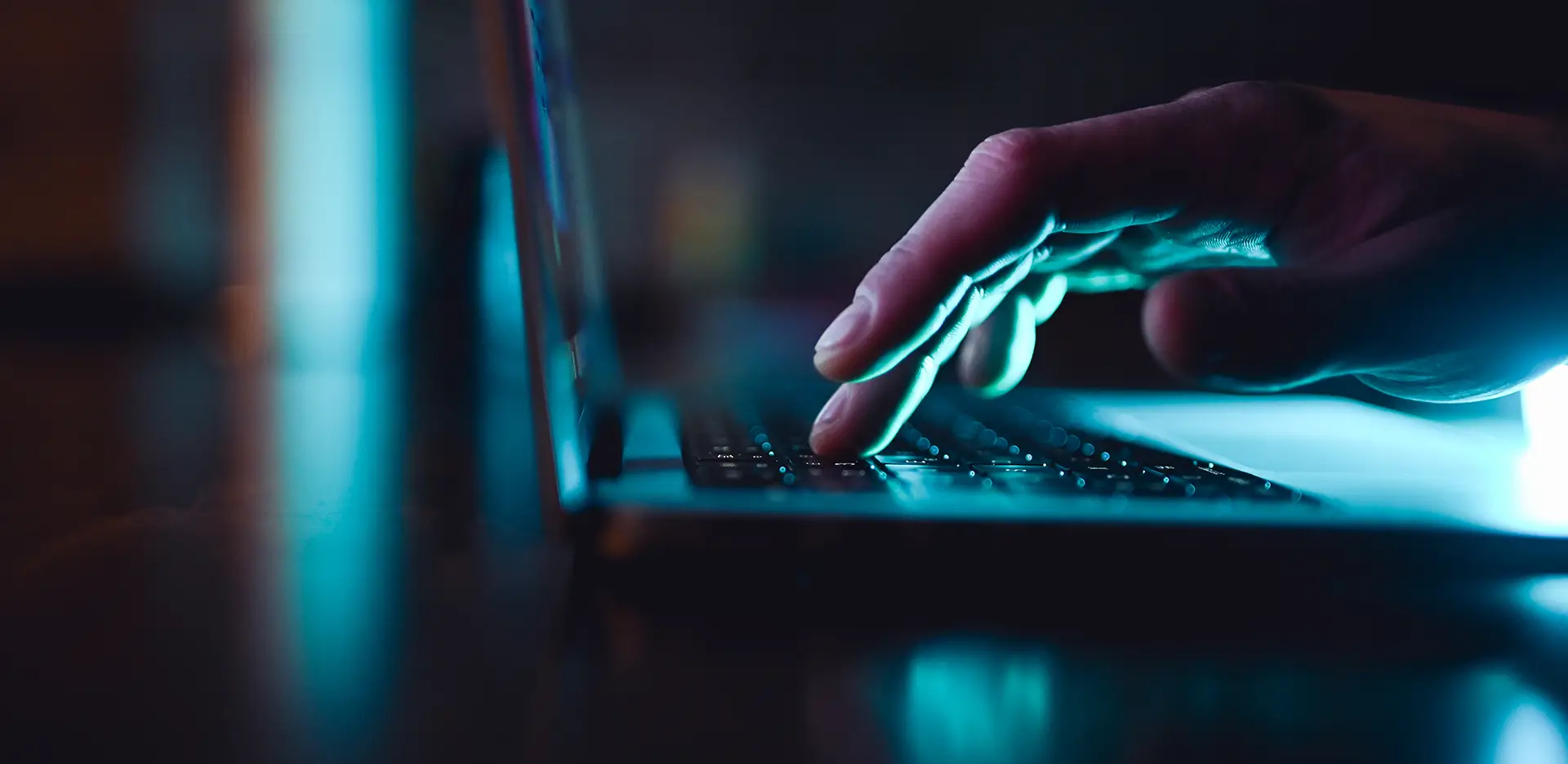 A hand typing at a laptop keyboard.
