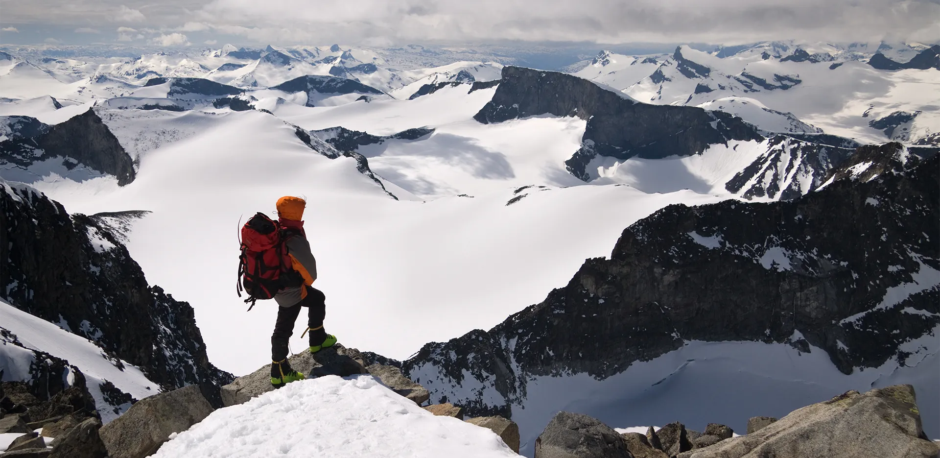 A hiker at the top of a snowy mountain range.