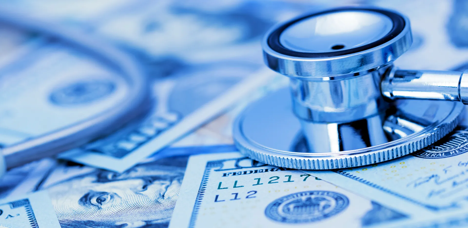A stethoscope laying across scattered 100 dollar bills.