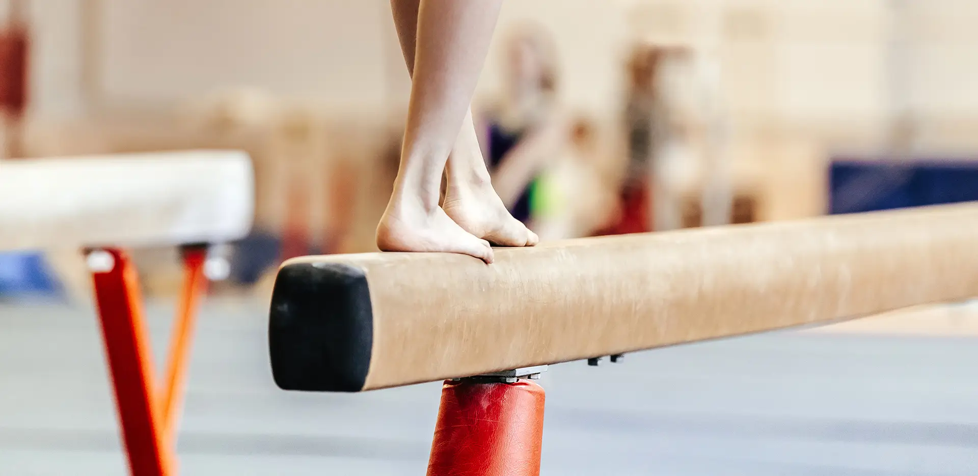 A gymnast standing on a balance beam.