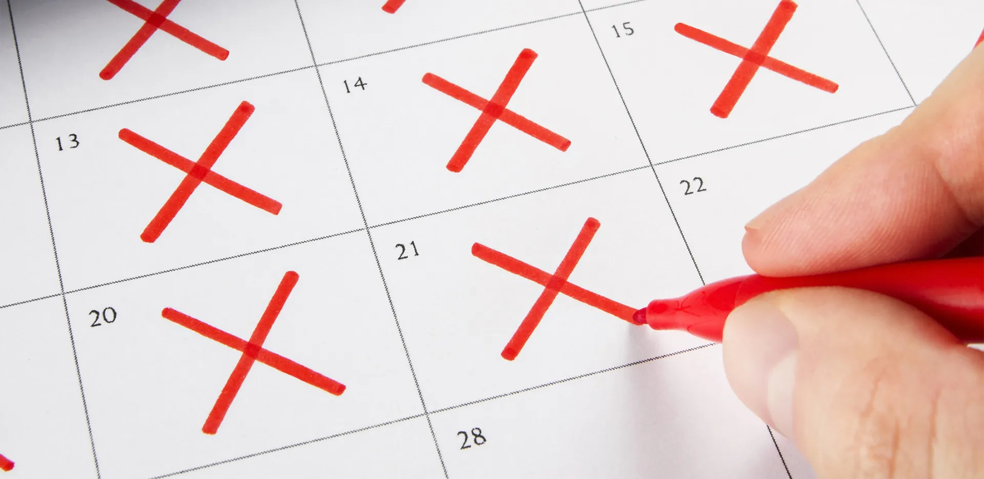 Someone crossing days off of a calendar in red pen.