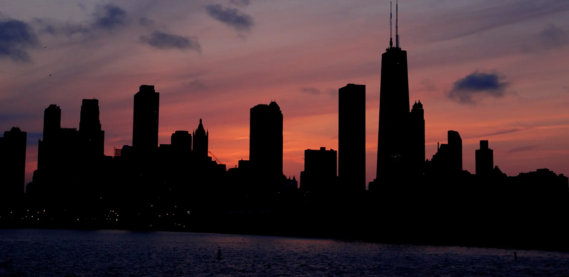 A dark city skyline at dusk with skyscrapers dark and unlit.