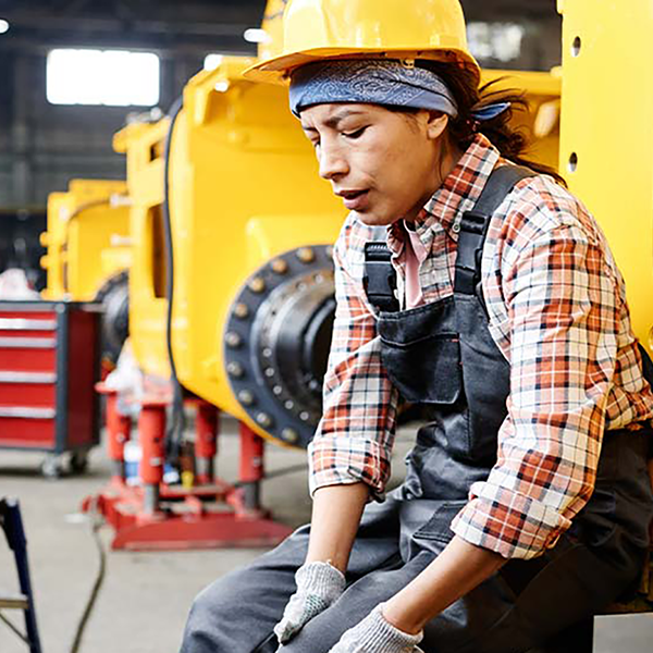 A construction worker sitting and clutching her knee.
