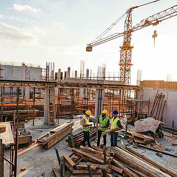 A trio of construction workers standing on a rooftop that's under construction.