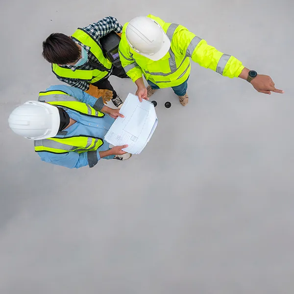 A bird's eye view of a trio of construction workers reviewing blueprints.