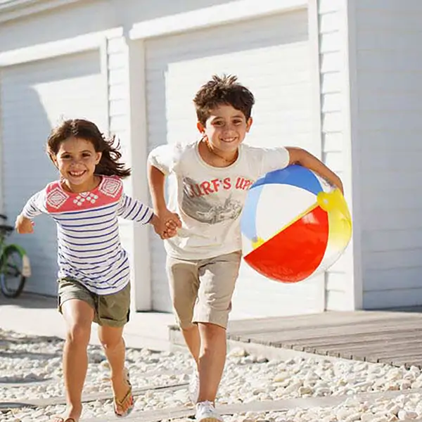 A family packing vacation supplies into a car in front of a rental home.