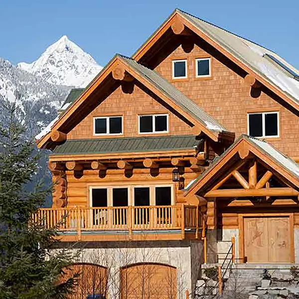 A log house in front of a mountain range.