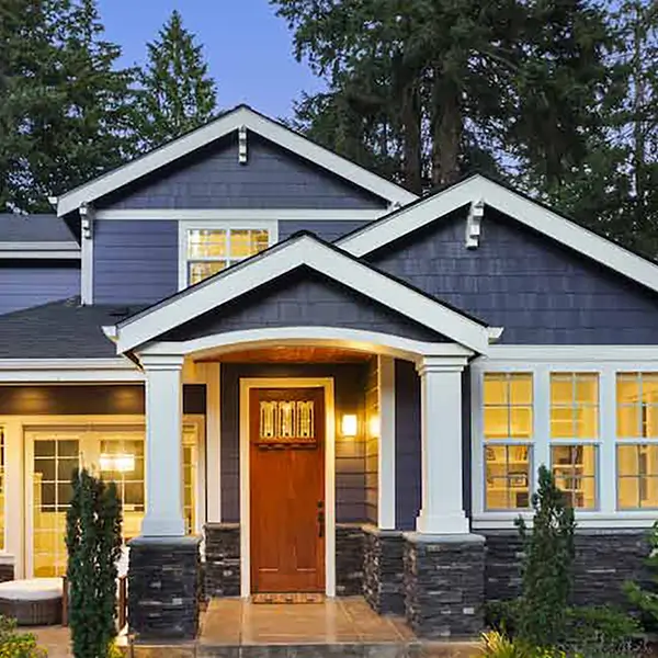 An exterior shot of a grey home with the lights on.