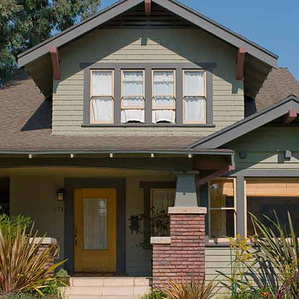 An exterior shot of a green-painted home in the daytime.
