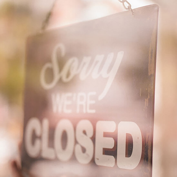 A close up of a woman hanging a 'Sorry We're Closed' sign.