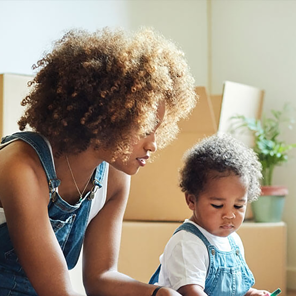 Parents sitting with their young toddler in front of moving boxes.