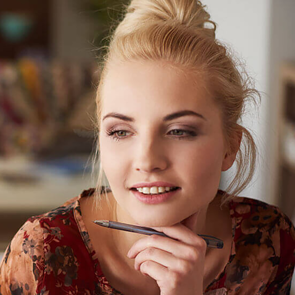 A woman holding a pen looking offscreen.