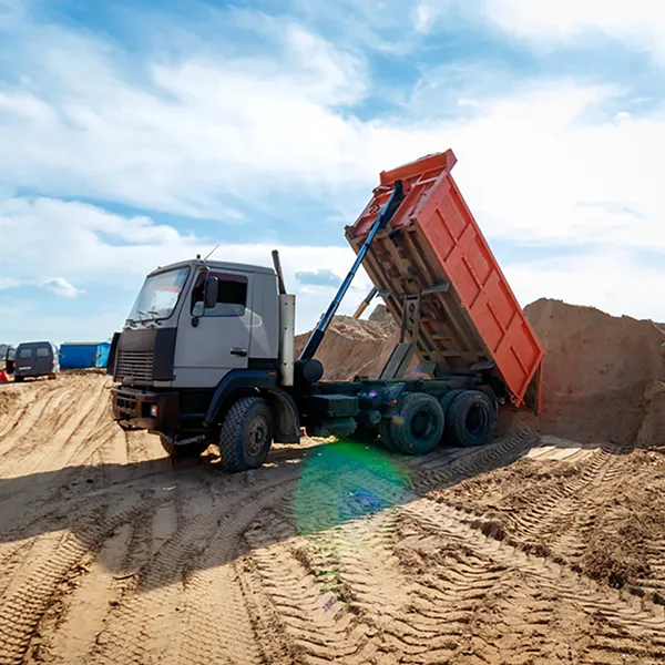 A dump truck unloading a load of sand.