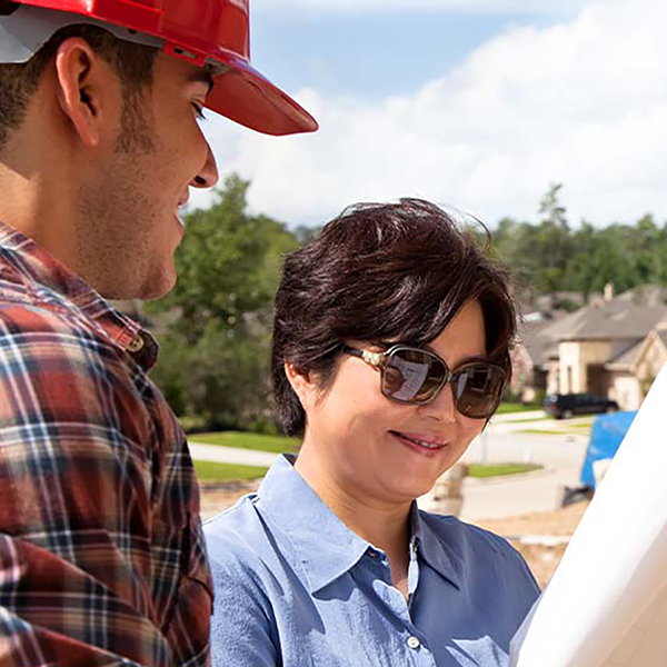 A homeowner and a contractor looking at a set of blueprints.